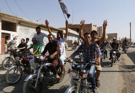 Residents of Tabqa city tour the streets on motorcycles, carrying flags in celebration after Tabqa air base fell to Islamic State militants, in nearby Raqqa city August 24, 2014. REUTERS/Stringer