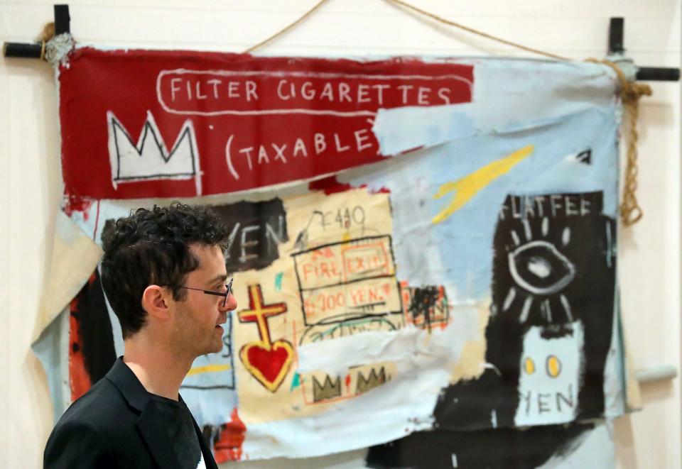 Curator Jeff Katzin explains how the "Keith Haring: Against All Odds" exhibit includes works by Haring's friends and contemporaries Wednesday, May 17, at the Akron Art Museum. Behind him is "One Million Yen" by Jean-Michel Basquiat.