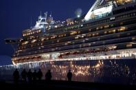 FILE PHOTO: Workers walk past the coronavirus-hit cruise ship Diamond Princess as they leave the Yokohama Port