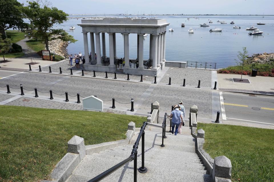 Pedestrians walk down stairs from Cole's Hill toward a pavilion that shelters Plymouth Rock, in Plymouth, Mass., Wednesday, June 9, 2021. Archaeologists are excavating the grassy hilltop that overlooks iconic Plymouth Rock one last time before a historical park is built on the site. (AP Photo/Steven Senne)