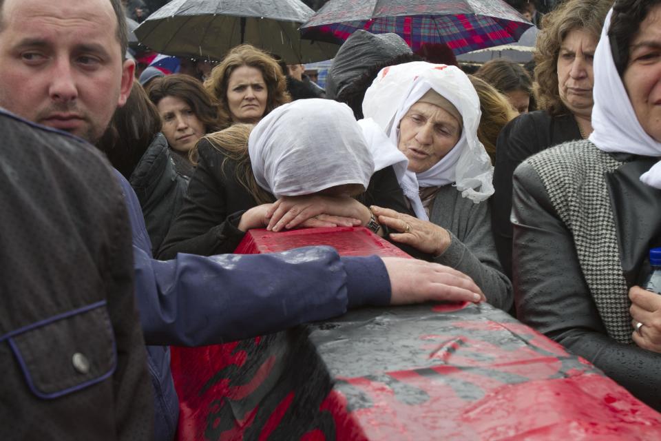 Ethnic Albanian woman weep on top of a coffin draped with the Albanian flag containing the remains of her relative killed during the 1998-99 Kosovo war in the town of Mala Krusa during the funeral ceremony on Wednesday, March 26, 2014. The victims were killed in two separate rampages by Serbs forces in town of Suva Reka and Mala Krusa just days after NATO began a bombing campaign to end an onslaught by Serbia on separatist ethnic Albanians. (AP Photo/Visar Kryeziu)