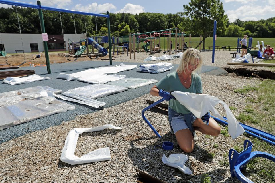 Volunteer Torrie Rochon, the principal at Hortonville Middle School, unpackages parts for a new playground at Hortonville Elementary School in August 2023.