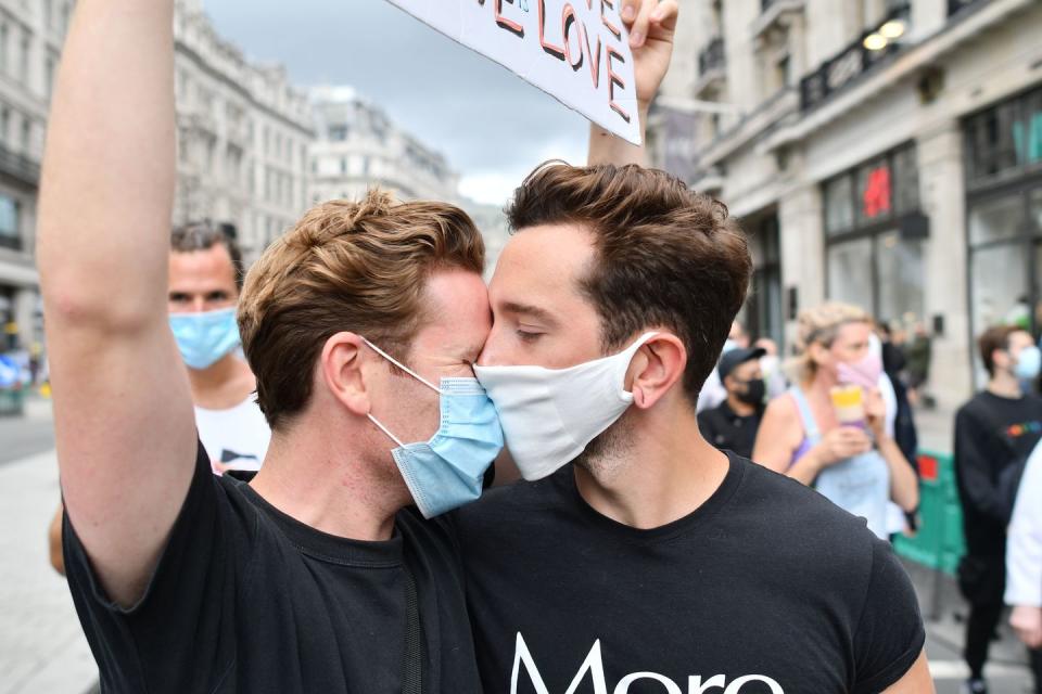 <p>Two supporters join veteran campaigners from the London Gay Liberation Front who held a socially distanced march along the route of the cancelled Pride march in London.</p>