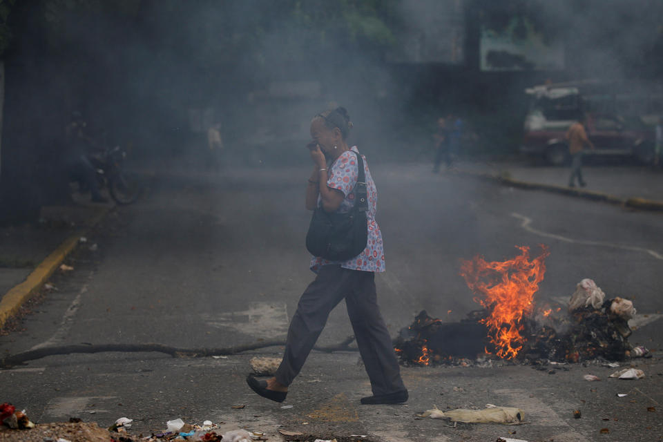 <p>A woman covers her face as she walks past a burning barricade during a protest against Venezuela’s President Nicolas Maduro’s government in Caracas, Venezuela May 2, 2017. (Photo: Carlos Garcia Rawlins/Reuters) </p>
