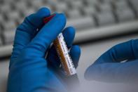 FILE - In this May 24, 2016 file photo an employee of the Russia's national drug-testing laboratory holds a vial in Moscow, Russia. Russia is accused of manipulating an archive of doping data from a laboratory in Moscow, which was meant to be a peace offering to the World Anti-Doping Agency to solve earlier disputes. (AP Photo/Alexander Zemlianichenko, File)