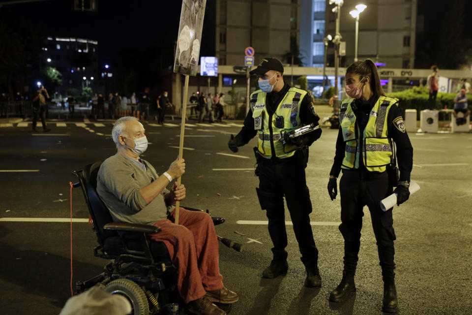 Police ask a protester in a wheelchair to move after security personnel forcibly cleared the square outside of Prime Minister Benjamin Netanyahu's residence in Jerusalem, early Sunday, Sept. 27, 2020, during a three-week nationwide lockdown in Israel to curb the spread of the coronavirus. (AP Photo/Maya Alleruzzo)