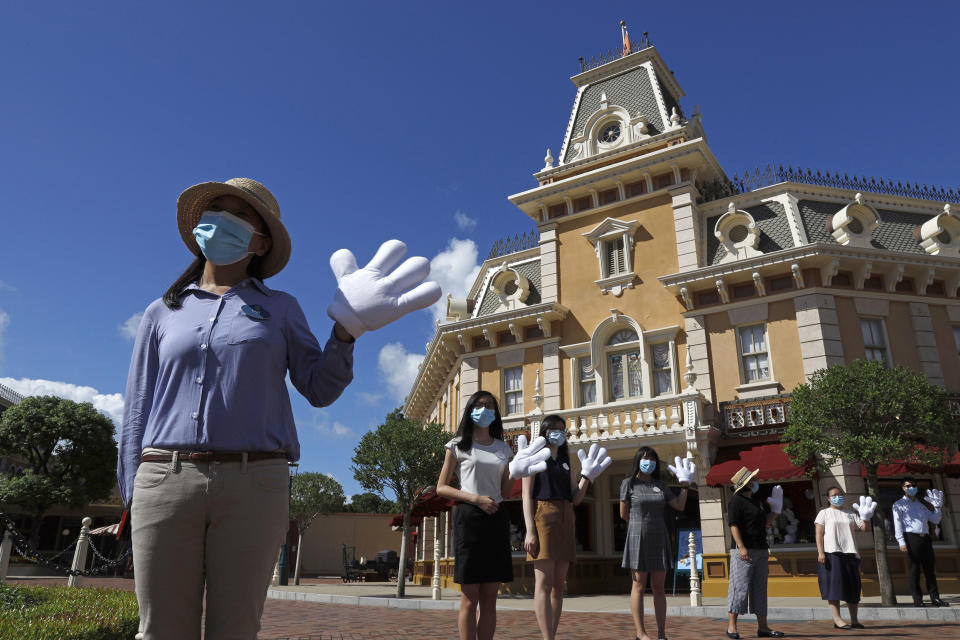 Empleados con mascarillas para evitar la propagación del nuevo coronavirus reciben a los visitantes en Disneyland Hong Kong, el jueves 18 de junio de 2020. El jueves, Disneyland Hong Kong abrió sus puertas a los visitantes por primera vez en casi cinco meses, con un aforo reducido y la implementación de medidas de distanciamiento social. El parque temático cerró temporalmente a finales de enero debido al brote de coronavirus y es el segundo parque de Disney que se vuelve a abrir en todo el mundo, después de Disneyland Shanghái. (Foto AP/Kin Cheung)