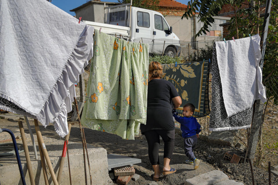 Azime Ali Topchu, 48, a Bulgarian Roma woman, walks with one of her nephews in a village on the outskirts of Burgas, Bulgaria, Monday, Sept. 28, 2020. Human rights activists and experts say local officials in several countries with significant Roma populations have used the pandemic to unlawfully target the minority group, which is Europe's largest and has faced centuries of severe discrimination. Topchu said that the police-enforced lockdown of her village in Burgas, on Bulgaria's Black Sea Coast, made her family "really sad." (AP Photo/Vadim Ghirda)