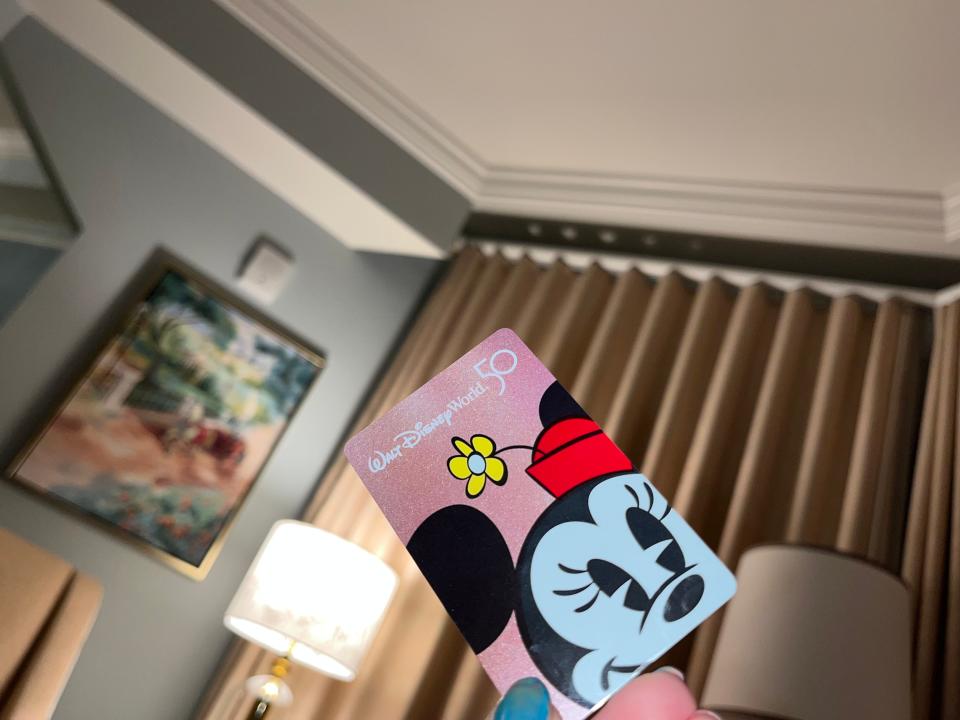 hand holding up minnie mouse room key inside a room at disney's grand floridian resort