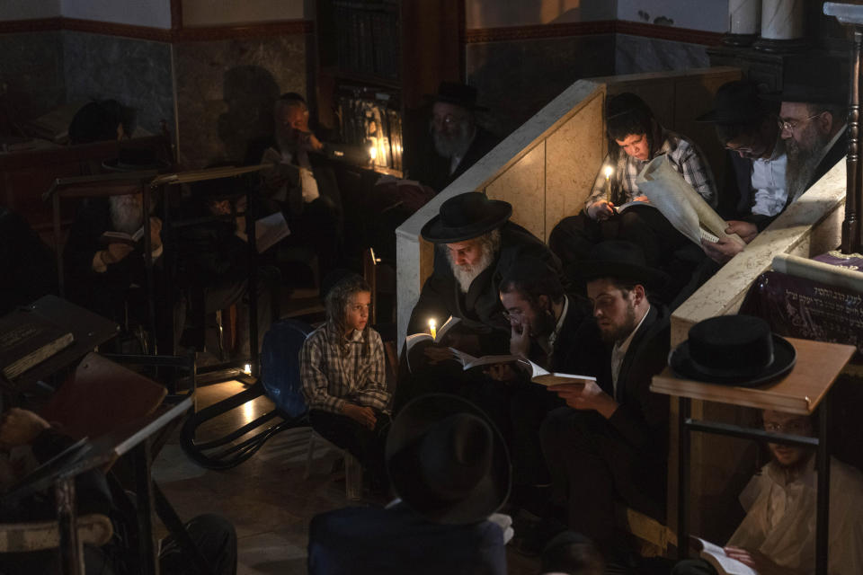 Ultra-Orthodox Jewish men and children read by candlelight from the book of Eicha (Book of Lamentations) during the annual Tisha B'Av (Ninth of Av) fasting and memorial day, commemorating the destruction of ancient Jerusalem temples in the Ultra-Orthodox neighborhood of Mea Shearim in Jerusalem, Wednesday, July 26, 2023. (AP Photo/Ohad Zwigenberg)