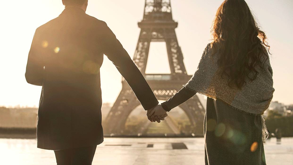 Couple holding hands in front of the Eiffel Tower in Paris