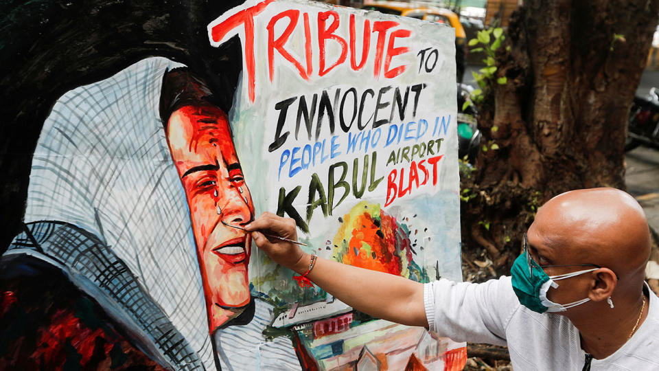 An artist outside an art school in Mumbai, India, paints a tribute to victims of the bomb blasts at the airport in Kabul. (Francis Mascarenhas/Reuters)