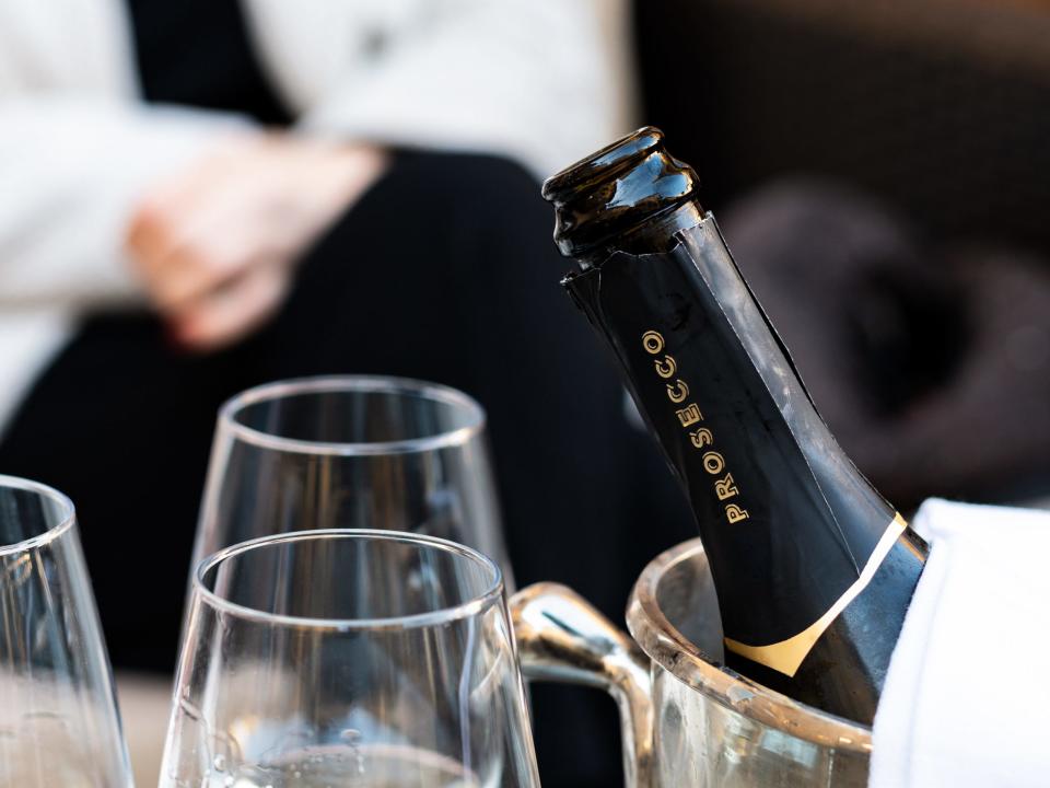 bottle of prosecco in an ice bucket next to wine glasses