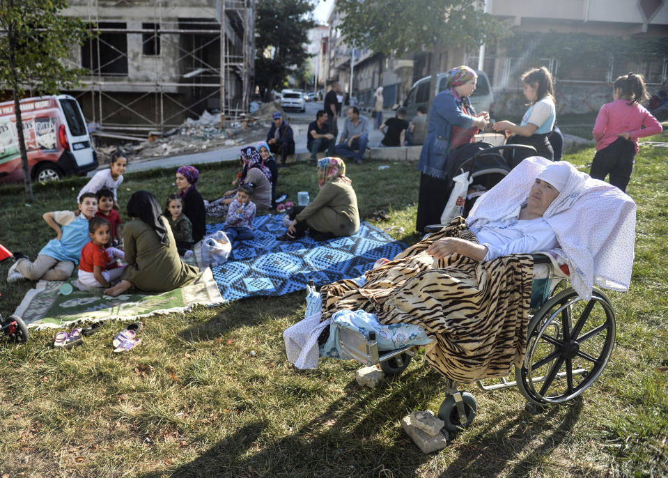 People sit in a grassy area after evacuating their homes, following an earthquake in Istanbul, Thursday, Sept. 26, 2019. Turkey's emergency authority says a 5,8 magnitude earthquake has shaken Istanbul with no immediate damage reported. Official Anadolu news agency, quoting the Istanbul governor's office, said there were no reports of damage. Experts have warned a major earthquake is expected to hit Istanbul, Turkey's most populous city with more than 15 million residents. (Ibrahim Mase/DHA via AP)