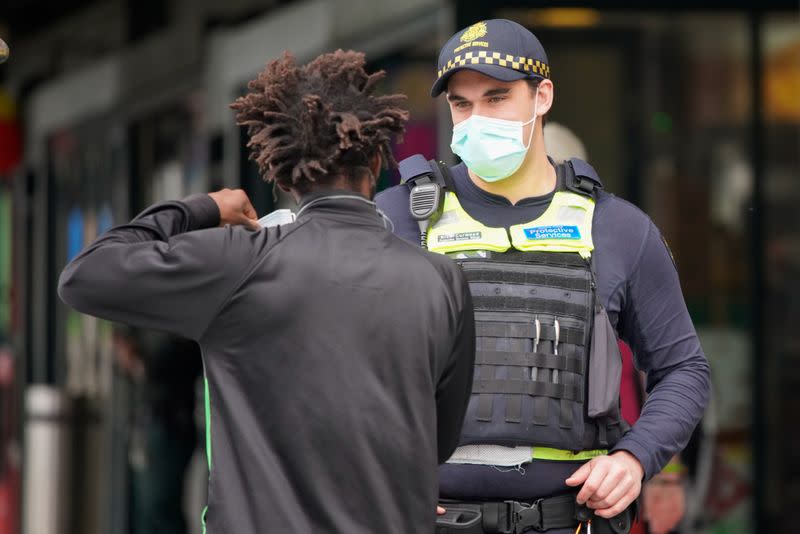 A Protective Services Officer wearing a face mask talks to a member of public in Melbourne, the first city in Australia to enforce mask-wearing to curb a resurgence of COVID-19