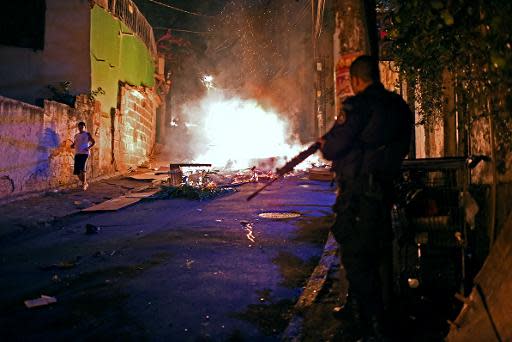 Un policía del Batallón de Operaciones Especiales vigila en una favela cercana a Copacabana, en Río de Janeiro, durante las protestas violentas el 22 de abril de 2014 (AFP | Christophe Simon)