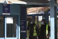 Security personnel wearing face masks stand at the gate of Attiko Hospital in Athens, Saturday, Feb. 29, 2020. Greek Health Ministry said all carnival events in Greece would be suspended as a precautionary measure. (AP Photo/Yorgos Karahalis)