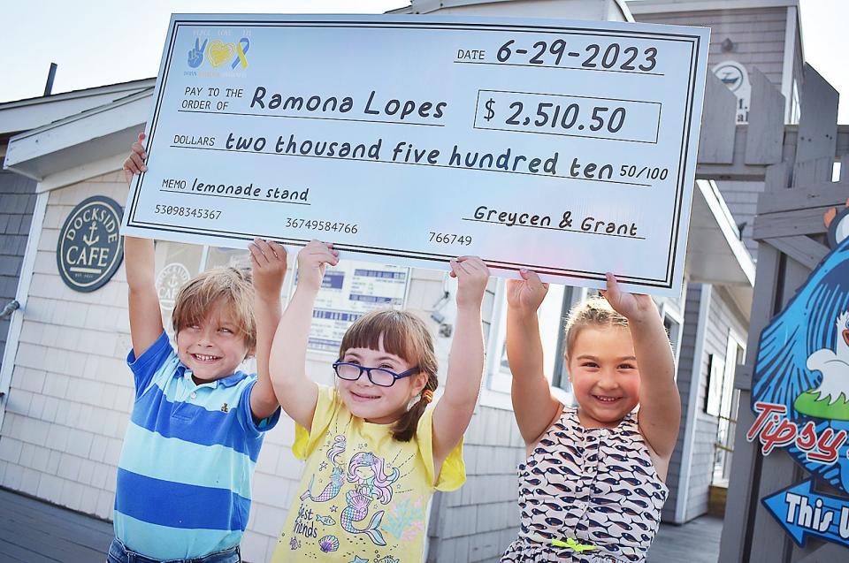 From left, Grant Pacheco, Ramona Lopes and Greycen Pacheco hold a giant check, made out to Lopes. Grant and Greycen recently set up a lemonade stand that earned more than $5,000, and they donated half the profits to their friend.