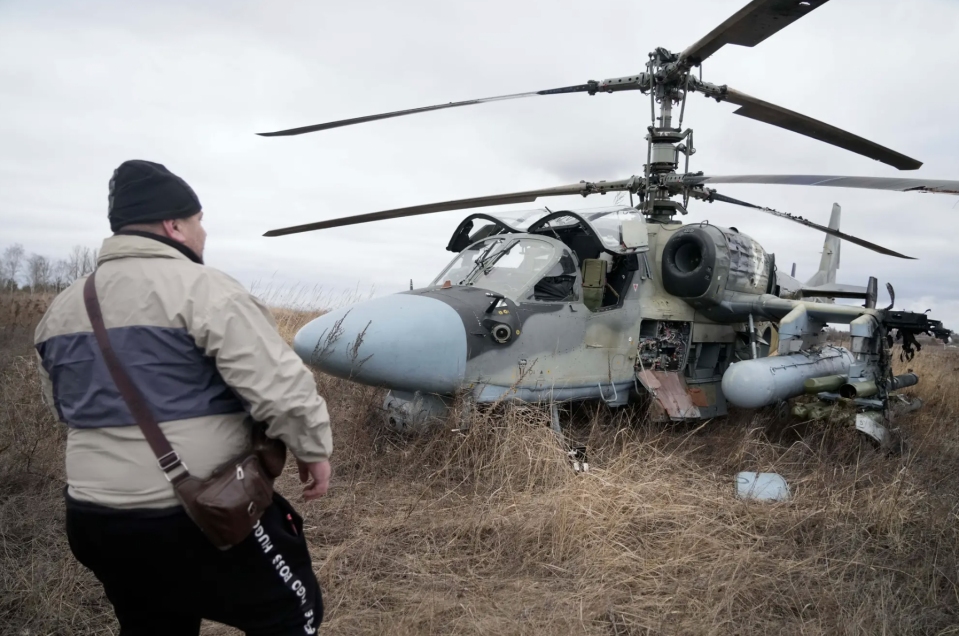 A man stands in front of a Russian Ka-52 forced to land in a field outside Kyiv, Ukraine, on February 24, 2022, on the first day of the full-scale invasion. <em>AP Photo/Efrem Lukatsky</em>