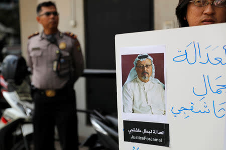 A policeman stands guard as an Indonesian journalist holds a placard during a protest over the disappearance of Saudi journalist Jamal Khashoggi in front of the Saudi Arabia embassy in Jakarta, Indonesia, October 19, 2018. REUTERS/Beawiharta/Files