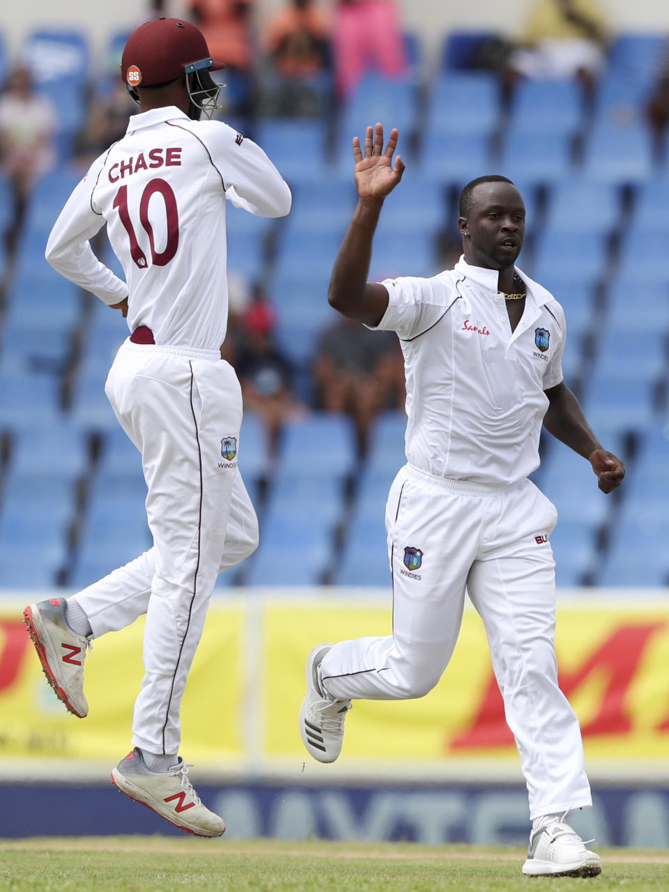 West Indies' bowler Kemar Roach celebrates with teammate Roston Chase the dismissal of India's Cheteshwar Pujara during day one of the first Test cricket match at the Sir Vivian Richards cricket ground in North Sound, Antigua and Barbuda, Thursday, Aug. 22, 2019. (AP Photo/Ricardo Mazalan)