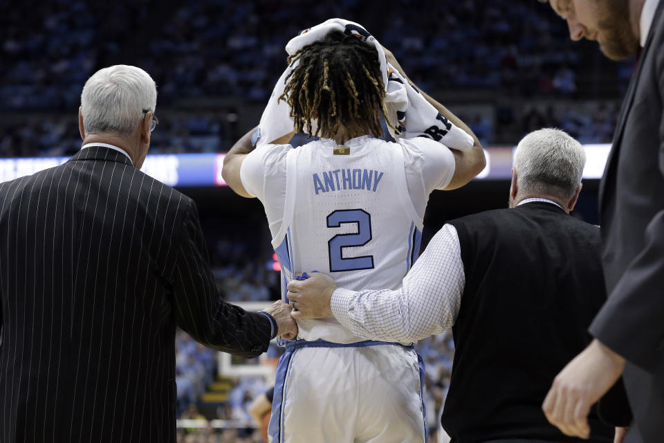 North Carolina guard Cole Anthony (2) is assisted by head coach Roy Williams, left, following an injury during the first half of an NCAA college basketball game against Ohio State in Chapel Hill, N.C., Wednesday, Dec. 4, 2019. (AP Photo/Gerry Broome)
