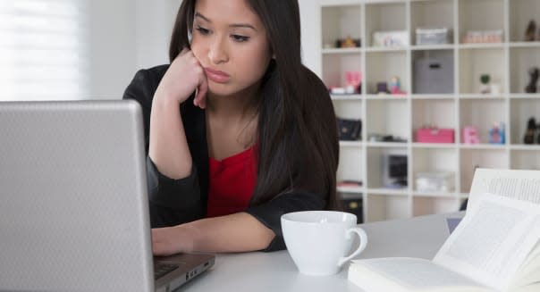 Bored mixed race businesswoman using laptop