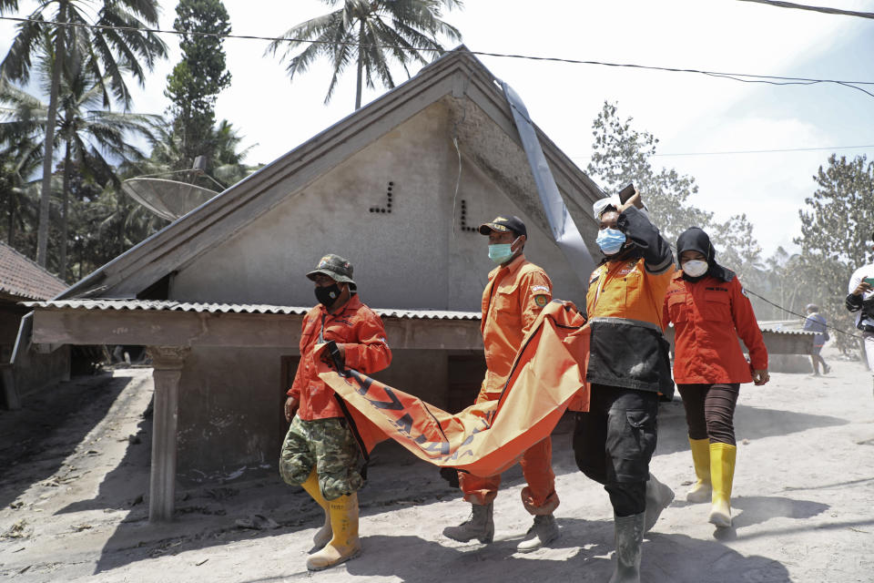 Rescuers carry a body bag containing the remains of a victim in the eruption of Mount Semeru, in Candi Puro village, Lumajang, East Java, Indonesia, Tuesday, Dec. 7, 2021. Indonesia's president on Tuesday visited areas devastated by a powerful volcanic eruption that killed a number of people and left thousands homeless, and vowed that communities would be quickly rebuilt. (AP Photo/Trisnadi)