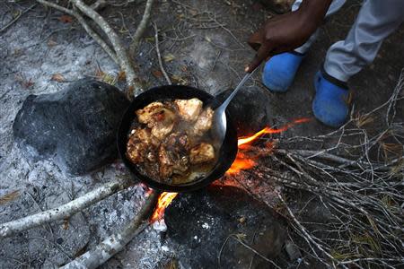 Marie, a migrant from Cameroon, cooks food at a clandestine campsite named Bolingo in northern Morocco near the border fence with Spain's north African enclave Melilla, November 28, 2013. REUTERS/Juan Medina