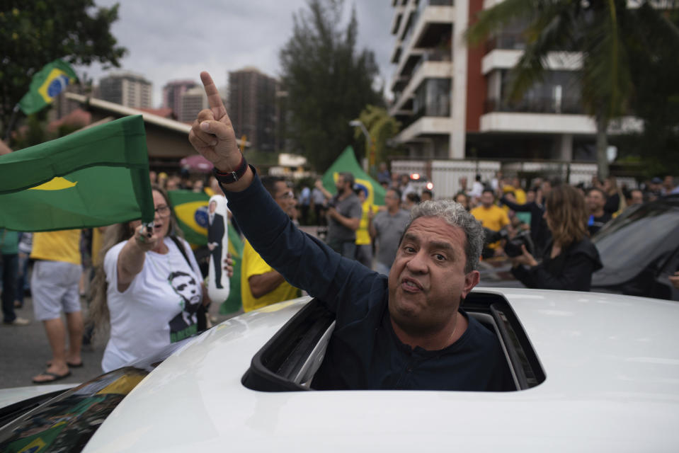 A supporter of Jair Bolsonaro, presidential candidate with the Social Liberal Party, show his support for the candidate in front of his house during the general elections in Rio de Janeiro, Brazil, Sunday, Oct. 7, 2018. (AP Photo/Ricardo Borges)