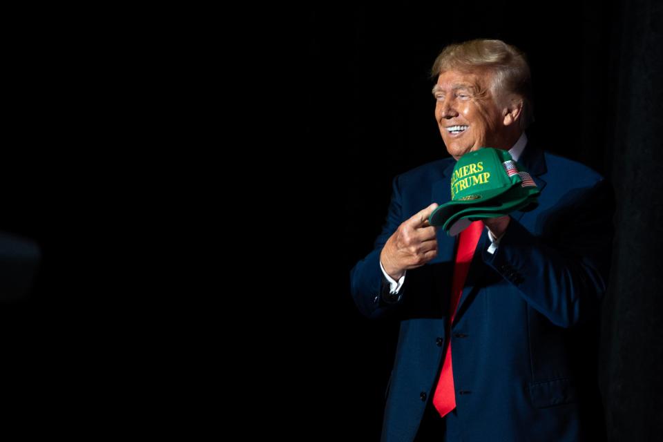 Former President Donald Trump holds up a Farmers for Trump hat during a campaign event Friday, July 7, 2023, at the Mid-America Center in Council Bluffs, Iowa.