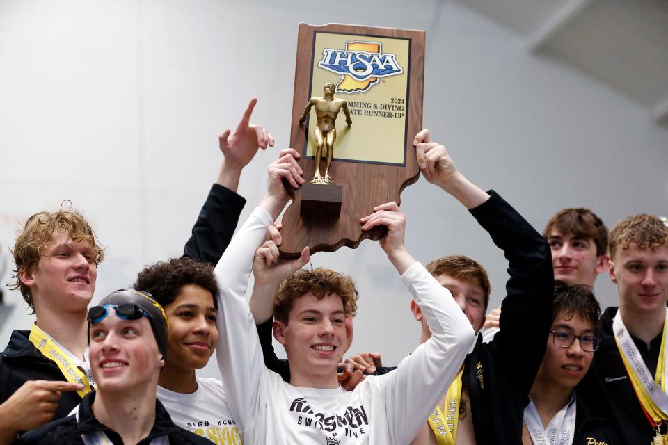 Penn senior Alex Fleming raises the state runner-up trophy as he and his teammates celebrate following the IHSAA boys swimming state championship meet Saturday, Feb. 24, 2024, at the IU Natatorium in Indianapolis.