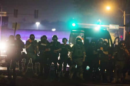 Police officers line up across the street as they maintain their distance from protesters during on-going demonstrations to protest against the shooting of Michael Brown, in Ferguson, Missouri, August 16, 2014. REUTERS/Lucas Jackson