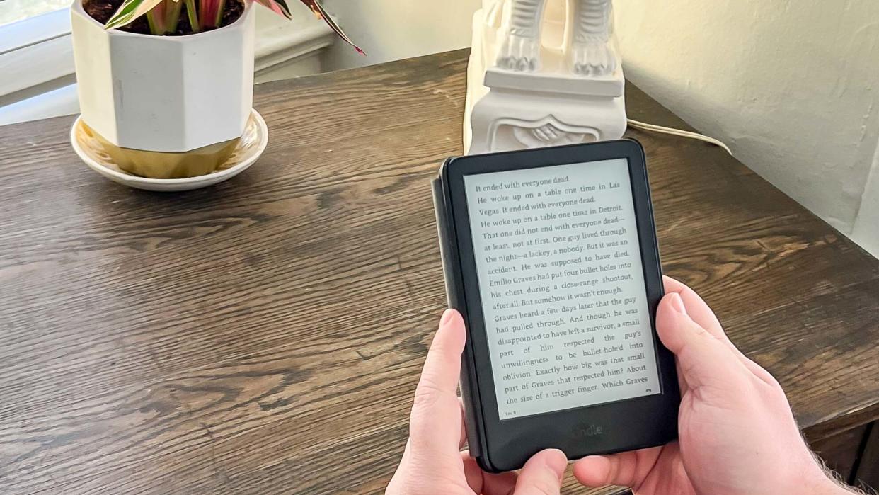  Amazon Kindle (2022) held in hand at a desk while open to an ebook page of text 