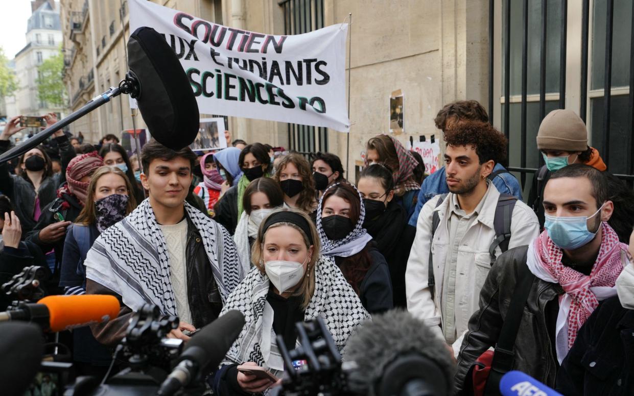 Demonstrators wearing Palestinian keffiyehs speak to the press under a banner reading "support for Sciences Po students"