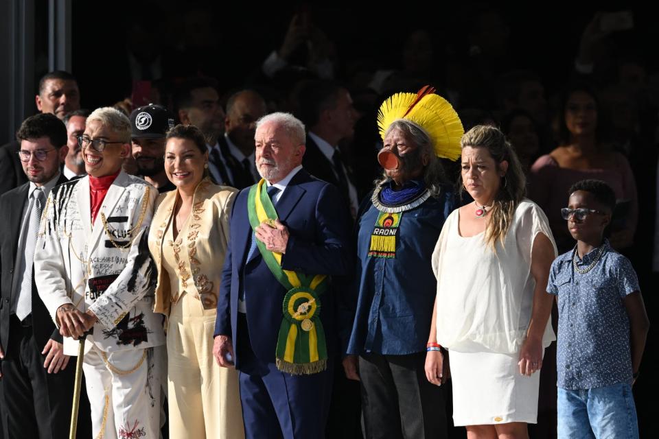 Lula reçoit son écharpe présidentielle lors de son investiture des mains d'un groupe de citoyens, dont le chef Raoni Metuktire, à Brasilia le 1er janvier 2023 - Evaristo SA / AFP