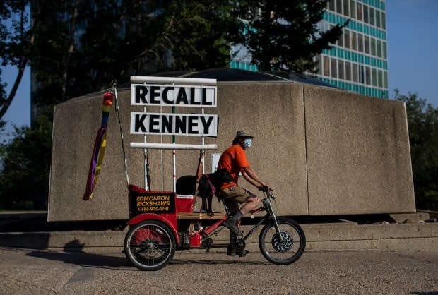 A man rides with a Recall Kenney sign during a protest in support of COVID-19 health orders in Edmonton. (Jason Franson/Canadian Press - image credit)