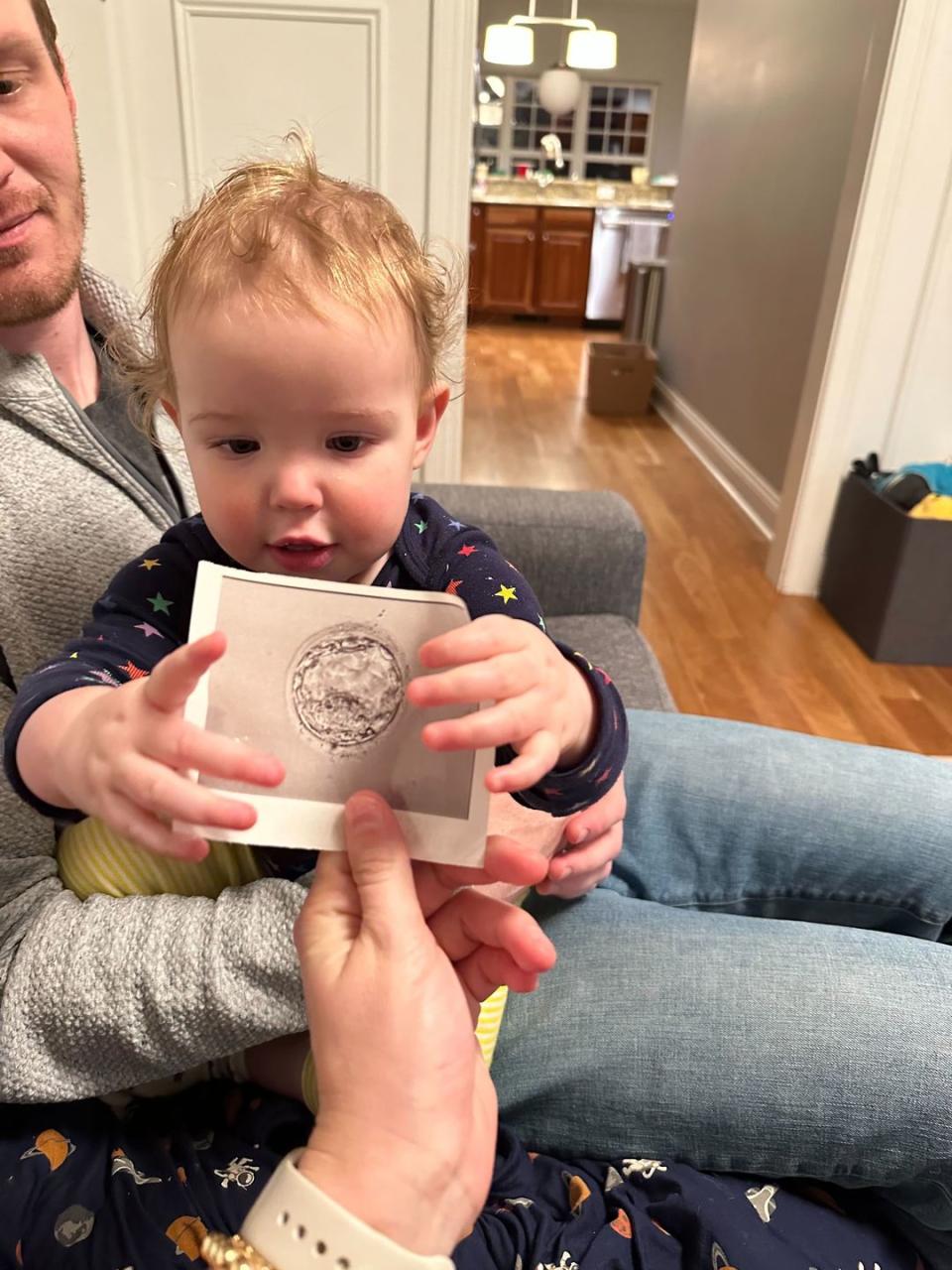 a baby holding up a paper photo