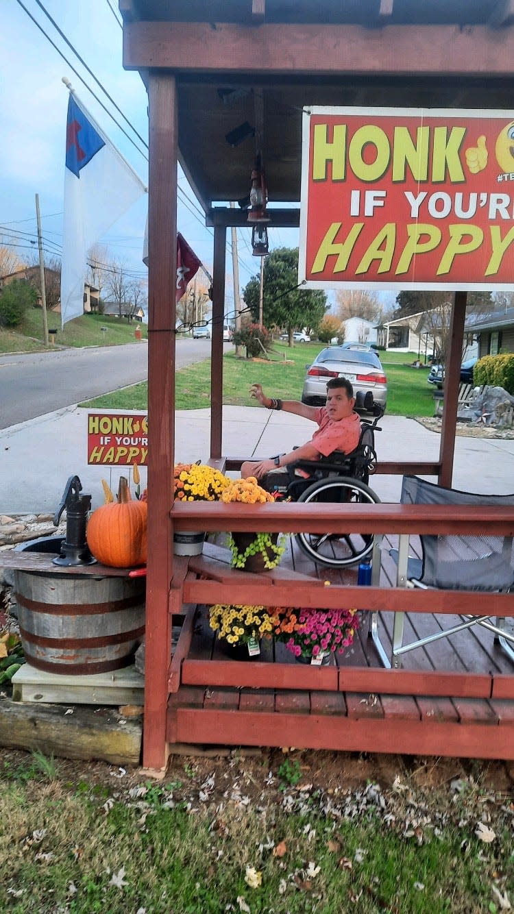 Jake Stitt, 17, waves at cars as he sits outside next to his famous "honk if you're happy" signs in Morristown, Tenn.