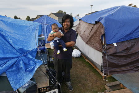 David Yu, 32, poses with his three and a half month old son Joseph, outside his tent at SHARE/WHEEL Tent City 3 outside Seattle, Washington October 8, 2015. REUTERS/Shannon Stapleton