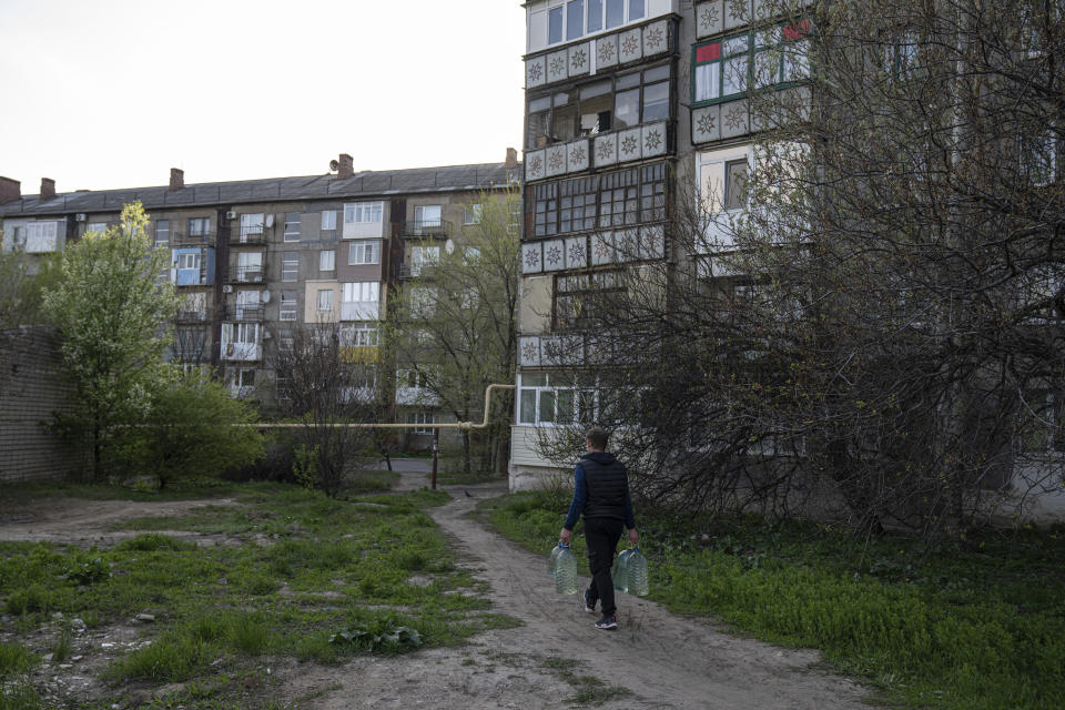 Andriy Cheremushkin carries cans with water in Toretsk, eastern Ukraine, Monday, April 25, 2022. Toretsk residents have had no access to water for more than two months because of the war. (AP Photo/Evgeniy Maloletka)