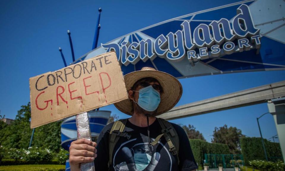 A man part of the coalition of resort labor unions holds a sign in front of Disneyland Resort in Anaheim, California, calling for higher safety standards before its reopening last Friday.