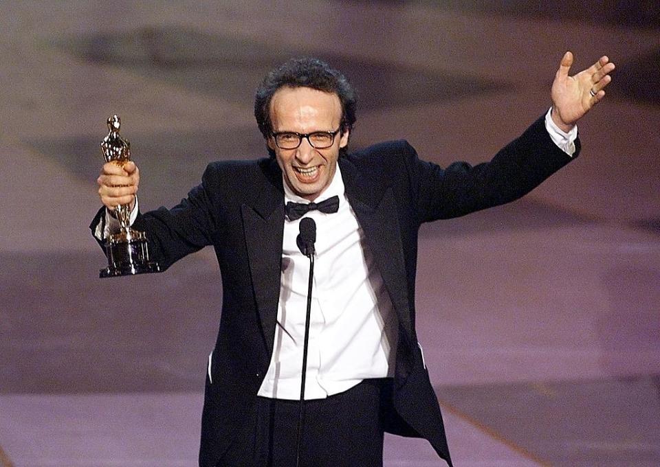 Robert in a tuxedo happily holding up his award onstage