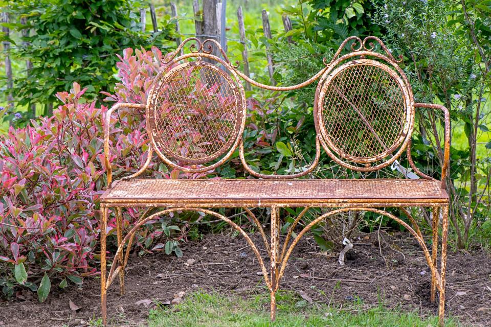 Close-up image of a shabby chic, rustic, rusty wrought iron garden bench/seat.