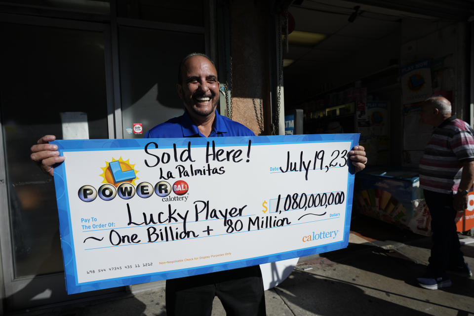 Lottery official Rick Herrera holds an enlarged check outside the Las Palmitas Mini Market where the winning Powerball lottery ticket was sold in downtown Los Angeles, Thursday, July 20, 2023. The winning ticket for the Powerball jackpot is worth an estimated $1.08 billion and is the sixth largest in U.S. history and the third largest in the history of the game. . (AP Photo/Marcio Jose Sanchez)