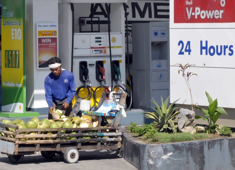 This file photo taken on April 10, 2008 shows a street vendor selling coconuts outside a petrol station in Manila. The Philippines is the world's biggest exporter of coconut products. Supply is not a problem, with 350 million coconut trees growing from the beaches up to the hills and yielding 15 billion fruits a year