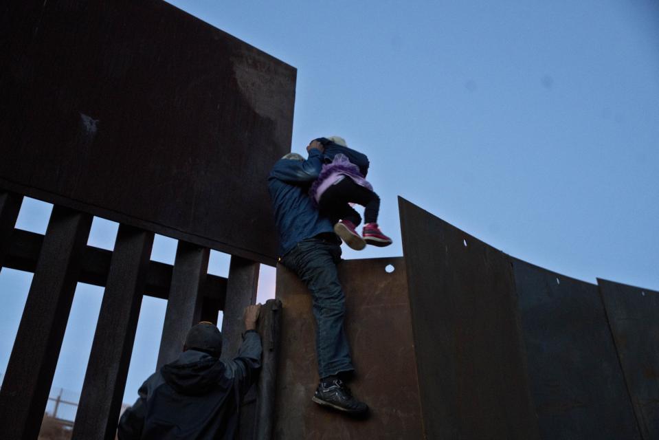 A Honduran migrant helps a young girl cross to the American side of the border wall, in Tijuana, Mexico, Sunday, Dec. 2, 2018. In November, President Donald Trump issued a proclamation suspending asylum rights for people who try to cross into the U.S. illegally from Mexico, although a divided U.S. appeals court has refused to immediately allow the Trump administration to enforce the ban. (AP Photo/Ramon Espinosa)