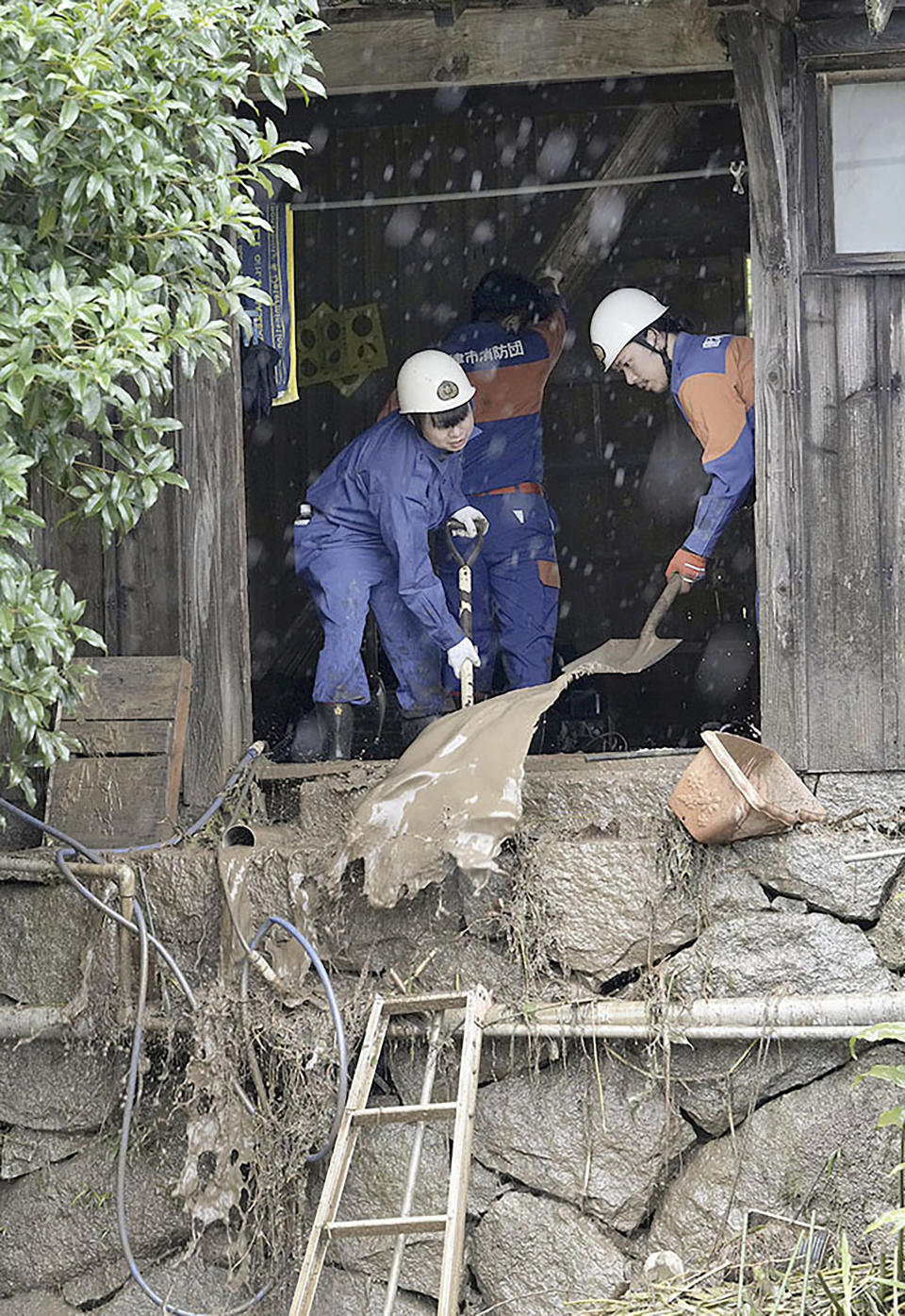 Firefighters scoop out the mud from a house damaged by a landslide in Karatsu, Saga prefecture, southern Japan Monday, July 10, 2023. Torrential rain has been pounding southwestern Japan, triggering floods and mudslides. (Kyodo News via AP)