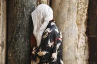 A woman prays in front of the closed Church of the Holy Sepulchre, a place where Christians believe Jesus Christ was buried in Jerusalem's Old City, Sunday, April 5, 2020. The traditional Palm Sunday procession was cancelled due to restrictions imposed to contain the spread of the coronavirus. (AP Photo/Ariel Schalit)