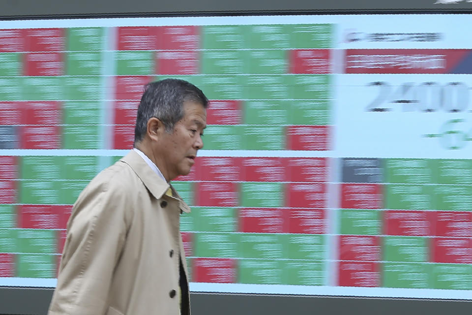 In this Wednesday, Dec. 18, 2019, photo, a man walks by an electronic stock board of a securities firm in Tokyo. Stocks were mixed in early trading in Asia on Friday, Dec. 20, 2019, after Wall Street posted more record highs, extending the market's gains for the week. (AP Photo/Koji Sasahara)